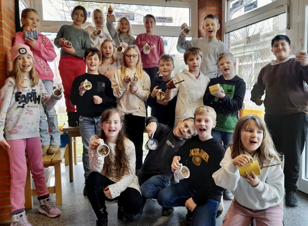Gruppenfoto mit Kindern der Klasse 3 b. Alle halten ihre selbt gebasteltet Tasse in die Kamera und freuen sich.