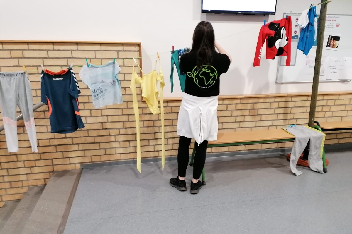 Schülering hängt Kleidung an Wäscheleine